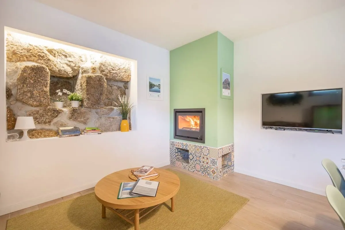Sala de estar da Casa Velha do Caminho com lareira e parede em pedra